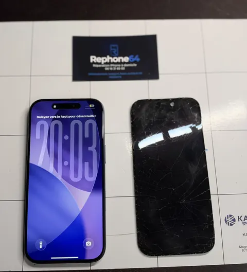 iPhone avec son écran neuf allumé, à côté de l’ancien écran brisé