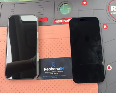 Ancien écran et iPhone réparé sur le tapis de travail, avec la carte REPHONE64